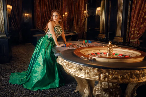 OKPK — A high-class gaming experience without limits A woman in a luxurious green gown next to an ornate roulette wheel, capturing the upscale casino mood of OKPK.